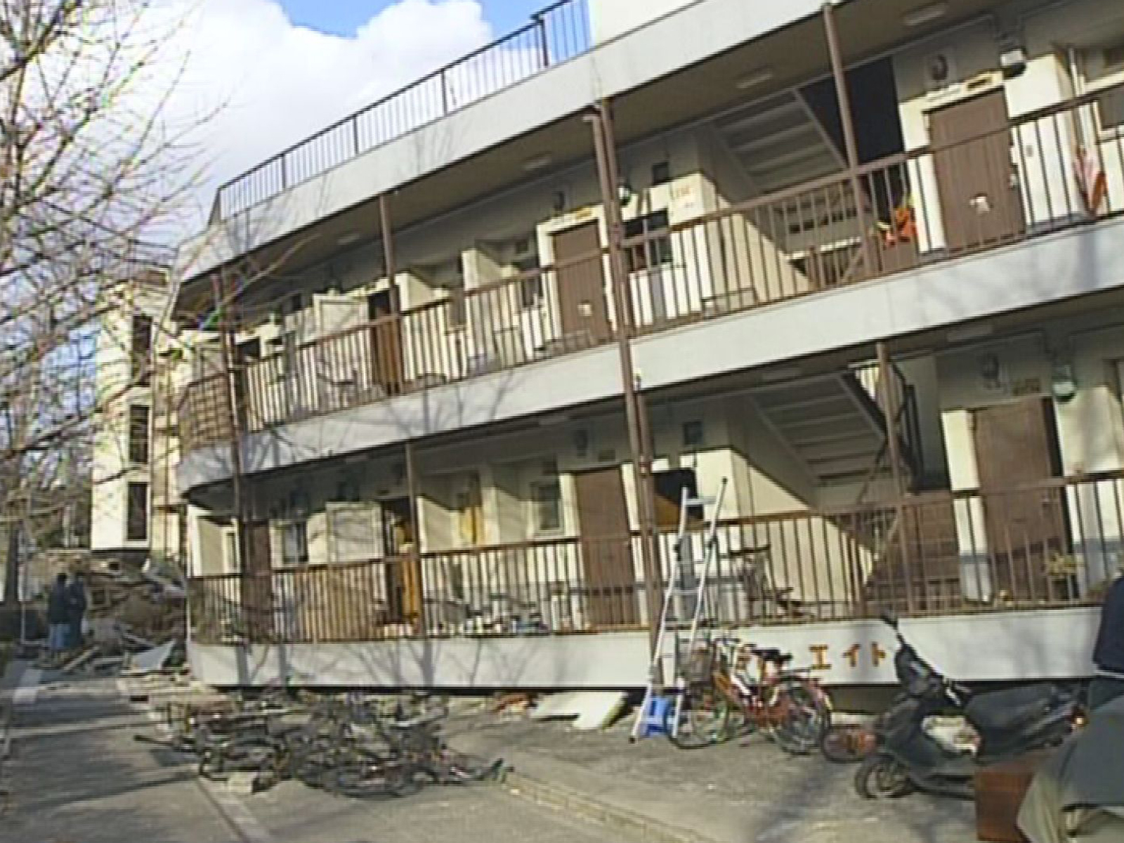 損壊した集合住宅の外観と、その周囲に残された倒壊物の状況。